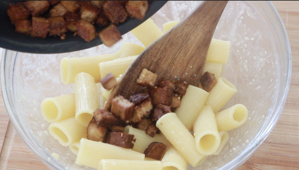 Aggiungi nella ciotola la pasta, il tofu affumicato e mischia bene. 